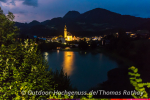 Abendlich illuminierte Kirche in Reith mit dem Badesee